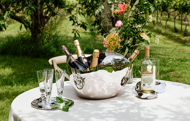 Drift Champagne Bucket with champagne bottles and glasses on a table outdoors.
